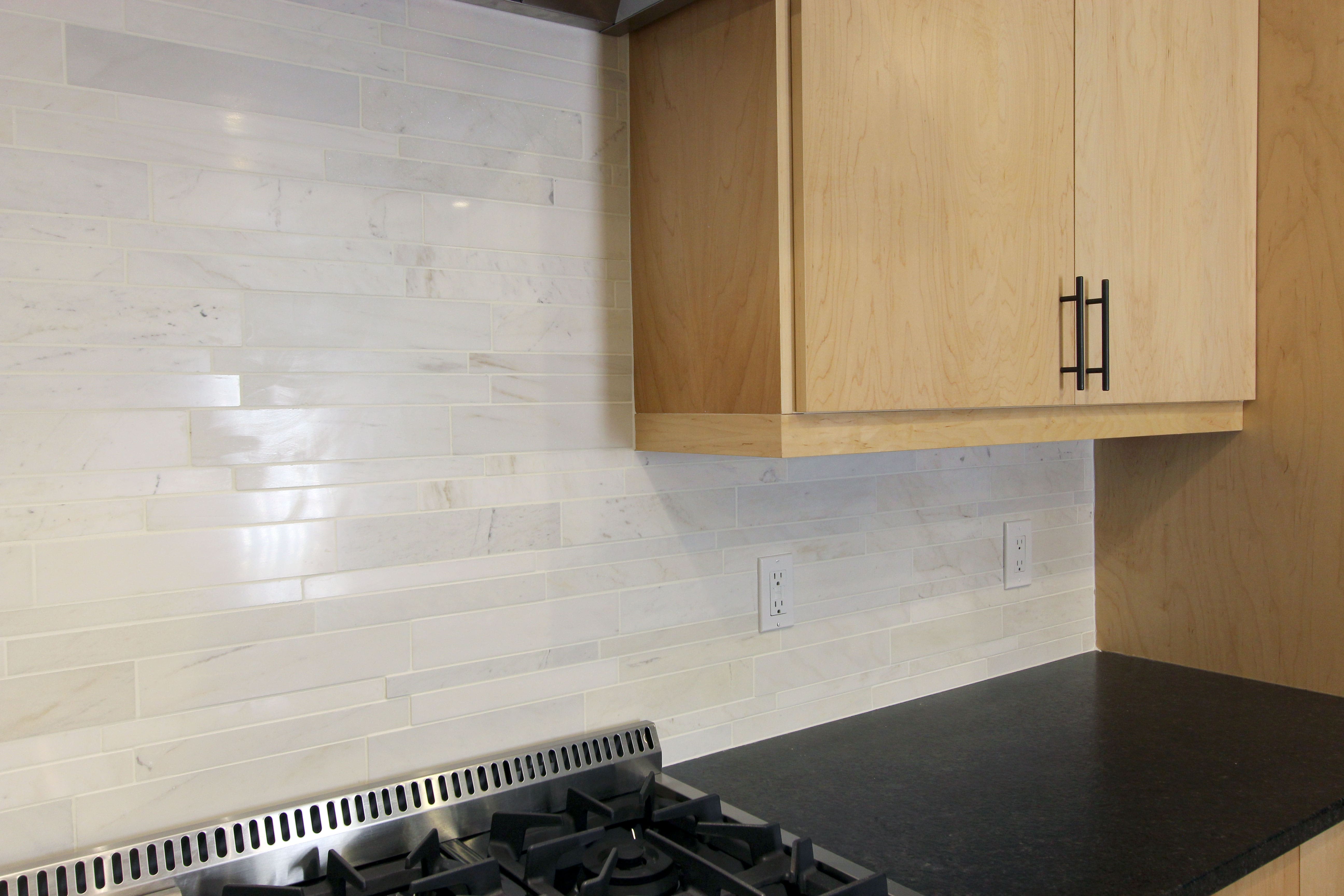 Norstone White Marble Lynia Interlocking Tiles used on a kitchen backsplash showing electric outlets extended out against the tile